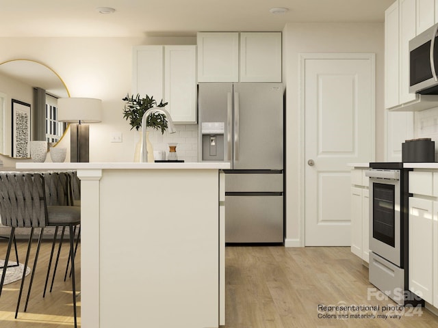 kitchen with appliances with stainless steel finishes, light wood-type flooring, tasteful backsplash, a breakfast bar, and white cabinetry