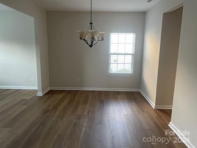 unfurnished dining area featuring a chandelier and dark hardwood / wood-style floors