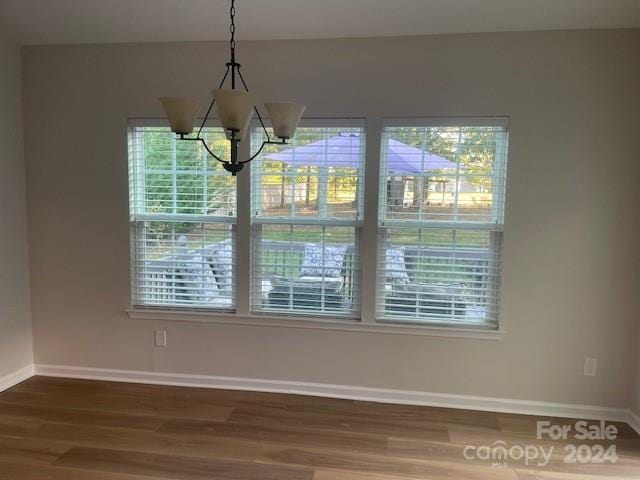 unfurnished dining area with dark hardwood / wood-style floors and a chandelier