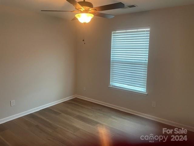 spare room with dark hardwood / wood-style flooring and ceiling fan