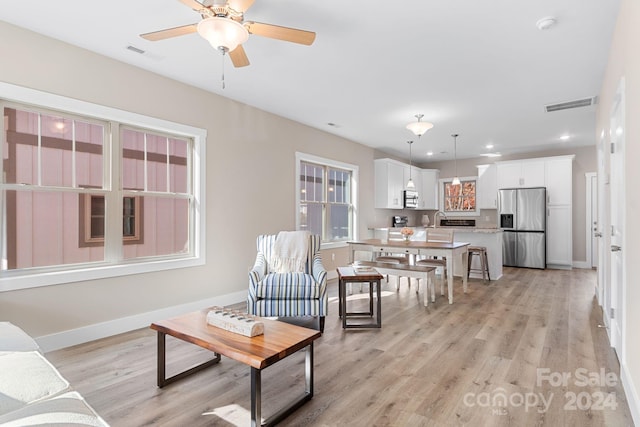 living room with light hardwood / wood-style flooring, ceiling fan, and sink