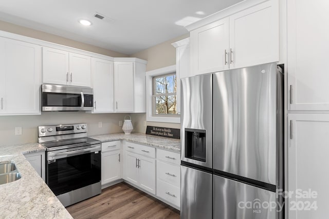 kitchen with stainless steel appliances, dark hardwood / wood-style floors, light stone countertops, sink, and white cabinets