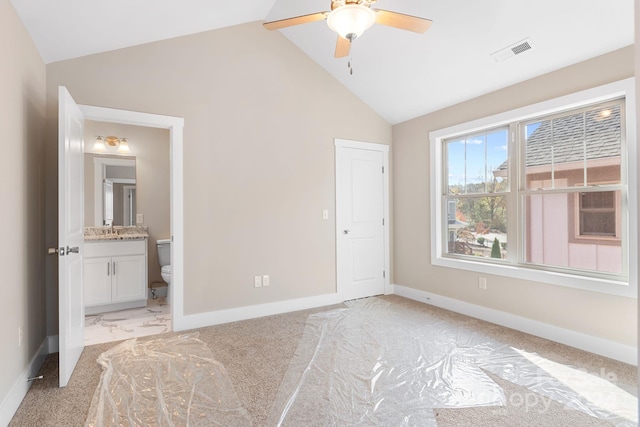 unfurnished bedroom with ensuite bath, light carpet, ceiling fan, and vaulted ceiling