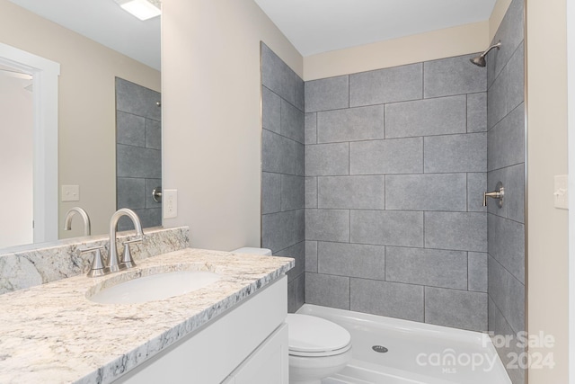 bathroom with vanity, toilet, and a tile shower