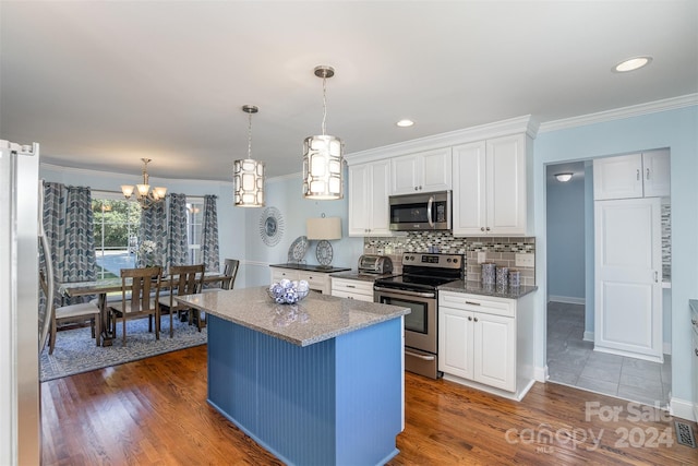 kitchen with crown molding, decorative light fixtures, a kitchen island, white cabinetry, and stainless steel appliances