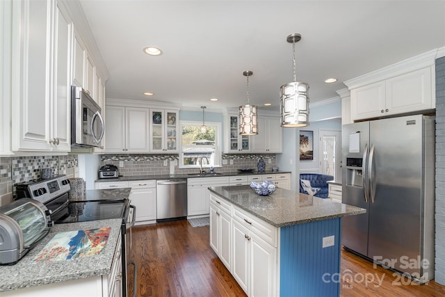 kitchen featuring stainless steel appliances, a kitchen island, white cabinetry, and sink