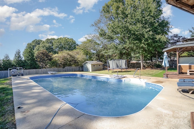 view of swimming pool featuring a diving board, a trampoline, a shed, a gazebo, and a patio