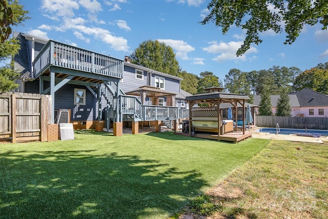 back of property featuring a gazebo, a swimming pool with hot tub, and a lawn