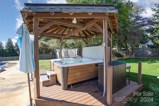 deck featuring a gazebo, a yard, and a hot tub