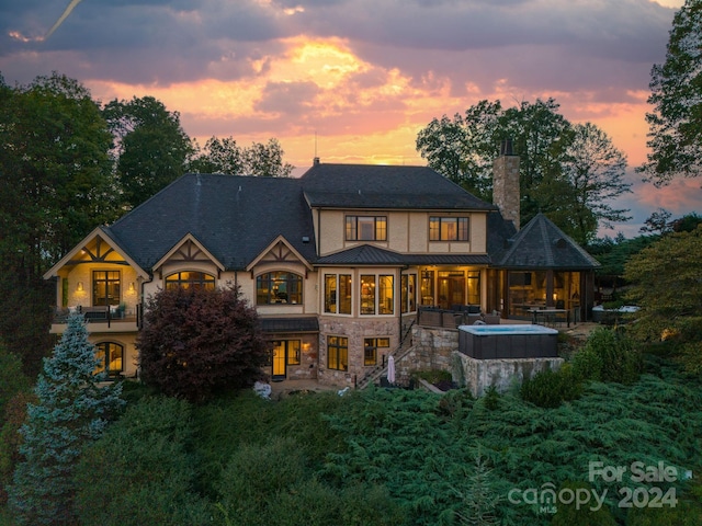 back house at dusk with an outdoor hot tub