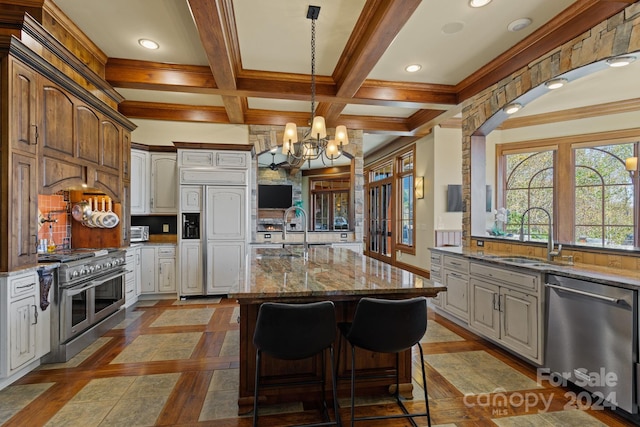 kitchen with premium appliances, tasteful backsplash, a center island with sink, sink, and white cabinets