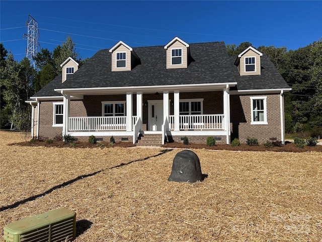 cape cod home featuring brick siding, crawl space, a shingled roof, and covered porch