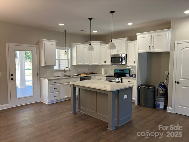 kitchen featuring a center island, white cabinetry, dark wood finished floors, stainless steel appliances, and a sink