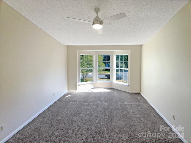 carpeted spare room featuring ceiling fan and a textured ceiling