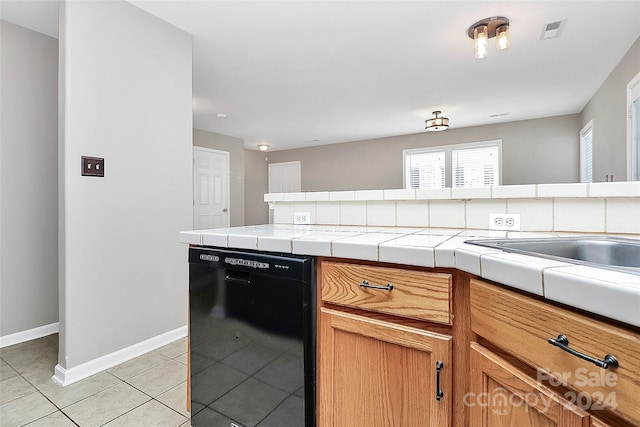 kitchen with tile countertops, light tile patterned floors, and black dishwasher