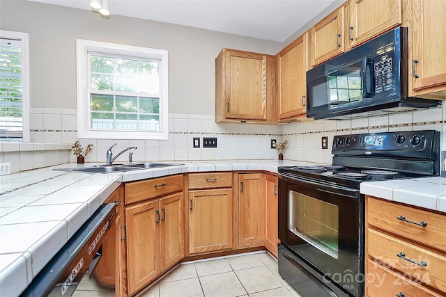 kitchen with black appliances, sink, light tile patterned floors, tasteful backsplash, and tile counters