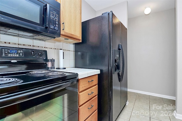 kitchen featuring tasteful backsplash, tile countertops, light tile patterned flooring, and black appliances