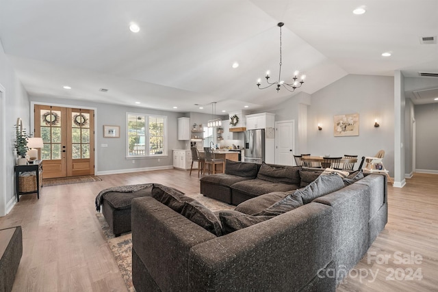 living room with french doors, a notable chandelier, vaulted ceiling, and light wood-type flooring