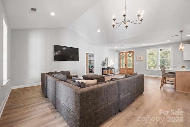 living room featuring an inviting chandelier, light hardwood / wood-style flooring, french doors, and lofted ceiling