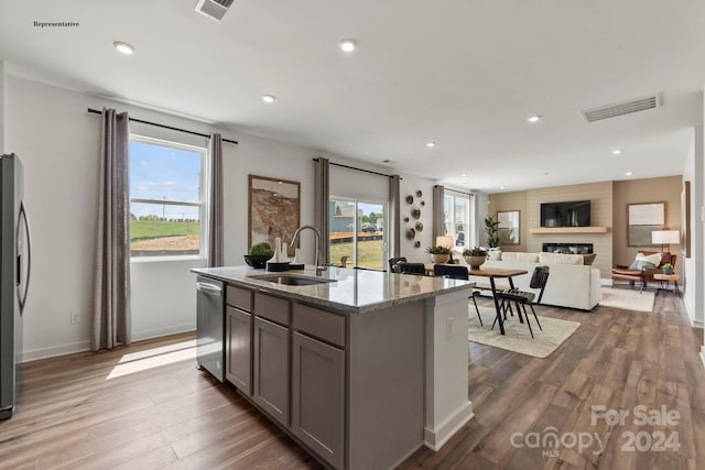 kitchen featuring a wealth of natural light, dark hardwood / wood-style floors, gray cabinetry, and a kitchen island with sink