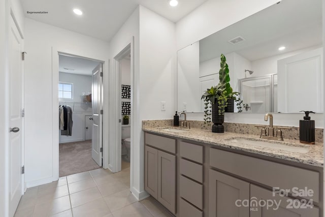 bathroom featuring toilet, tile patterned floors, vanity, and a shower with door