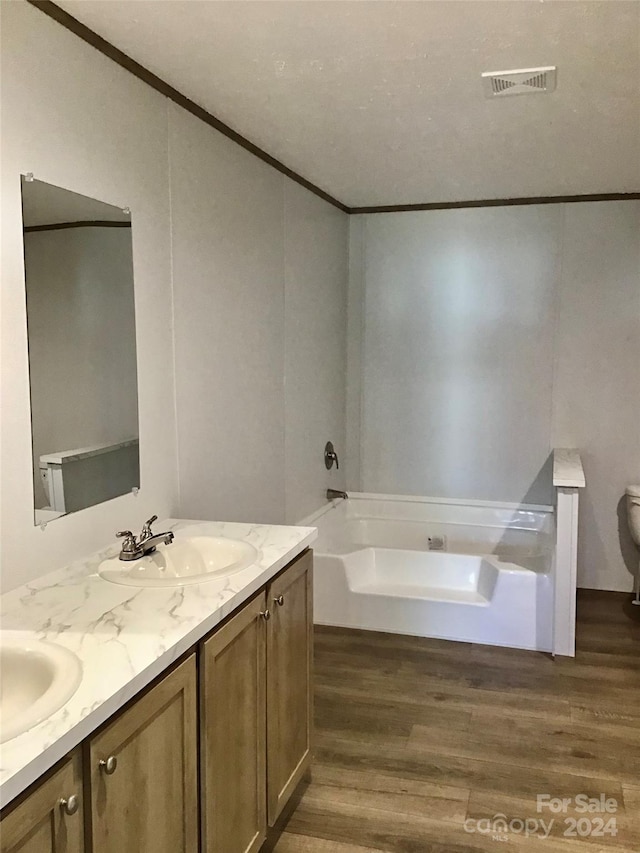 bathroom featuring hardwood / wood-style floors, toilet, a washtub, vanity, and crown molding