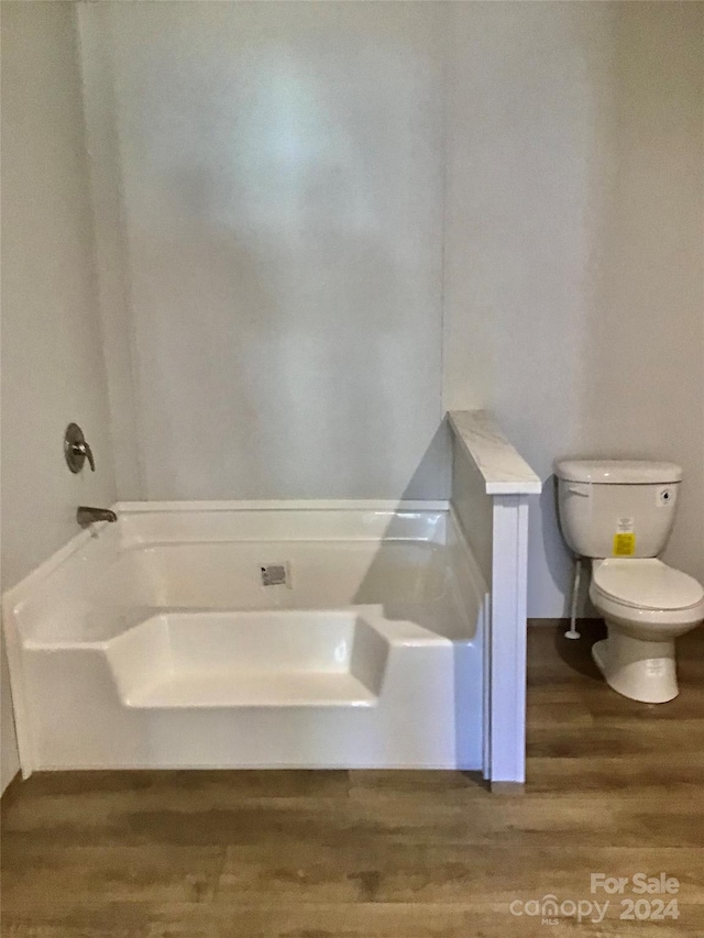 bathroom with a bathtub, hardwood / wood-style flooring, and toilet