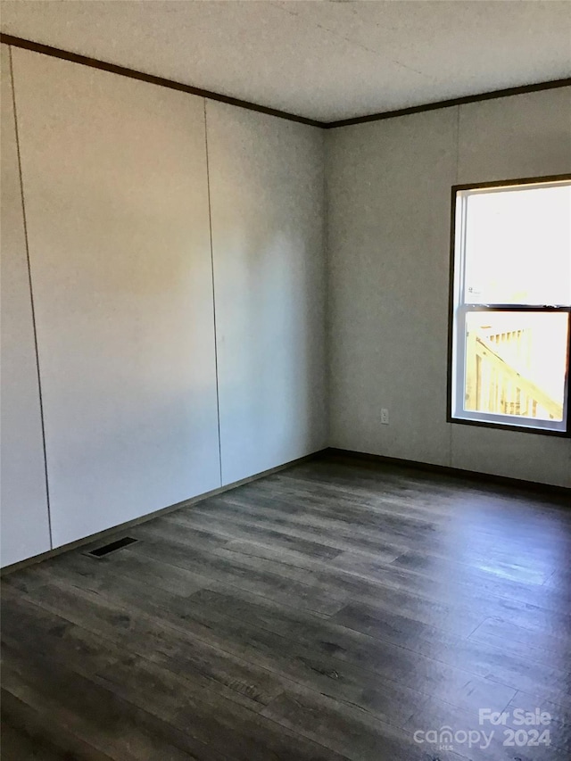 empty room with crown molding and dark hardwood / wood-style flooring