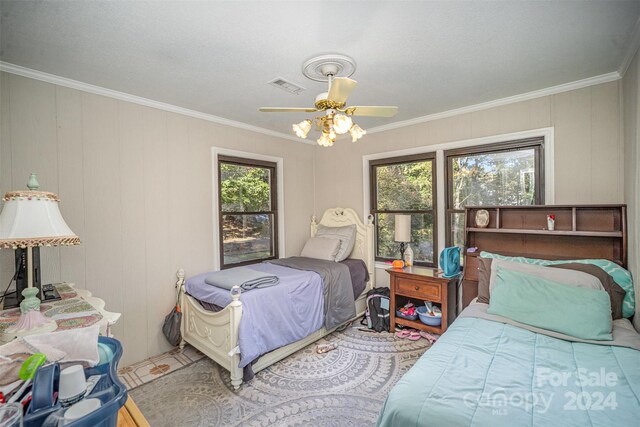 bedroom featuring ceiling fan, ornamental molding, and multiple windows