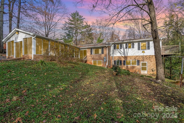 view of front of house with a yard and a sunroom