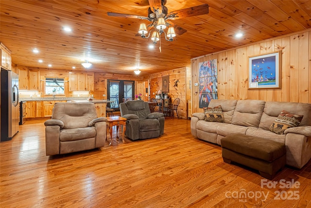 living room featuring wood walls, ceiling fan, light hardwood / wood-style floors, and wooden ceiling