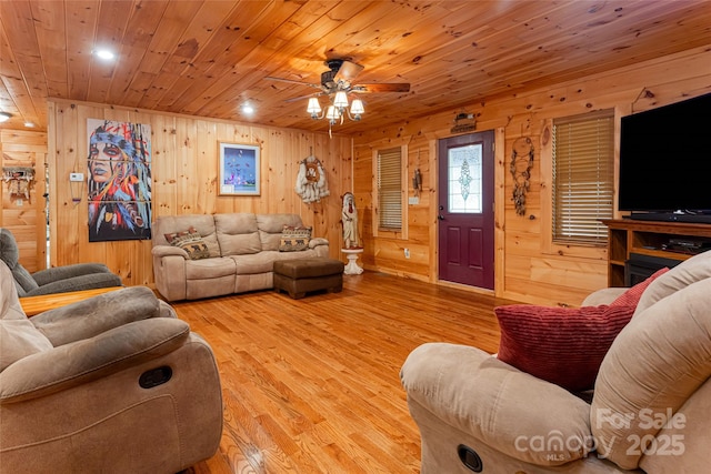 living room with wood walls, ceiling fan, light hardwood / wood-style floors, and wooden ceiling