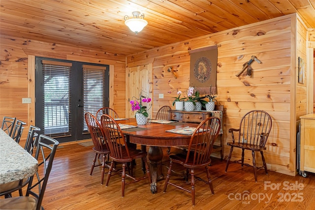 dining space with hardwood / wood-style floors, wood walls, and wooden ceiling