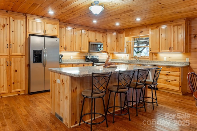 kitchen featuring light hardwood / wood-style flooring, light brown cabinetry, a kitchen island, wood ceiling, and appliances with stainless steel finishes