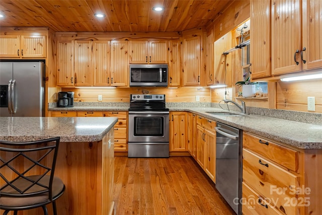 kitchen featuring a kitchen bar, appliances with stainless steel finishes, sink, light hardwood / wood-style floors, and a kitchen island