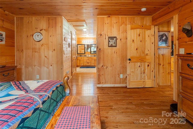 bedroom featuring wooden walls, light hardwood / wood-style flooring, and wooden ceiling