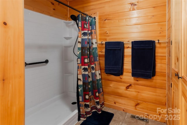 bathroom featuring a shower with shower curtain, tile patterned flooring, and wooden walls