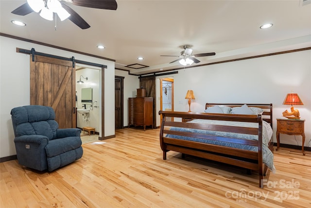 bedroom with a barn door, ensuite bathroom, crown molding, and light hardwood / wood-style floors