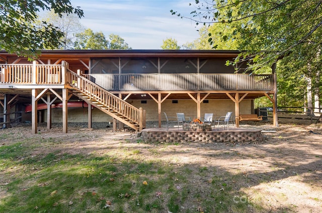 rear view of house featuring a wooden deck, a sunroom, and a patio