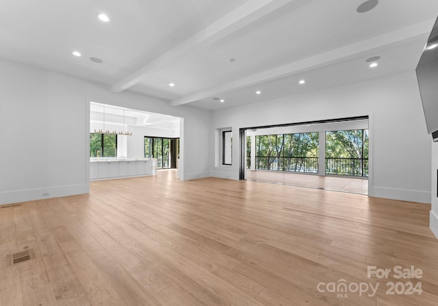 unfurnished living room featuring beamed ceiling, light hardwood / wood-style flooring, and a notable chandelier