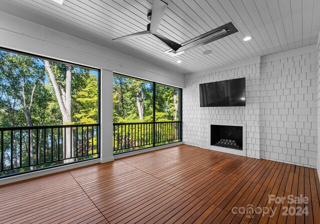 13702 Sage Thrasher Ln, Charlotte, NC 28278 - unfurnished living room featuring a ceiling fan, a fireplace, wooden ceiling, a skylight, and view of wooded area