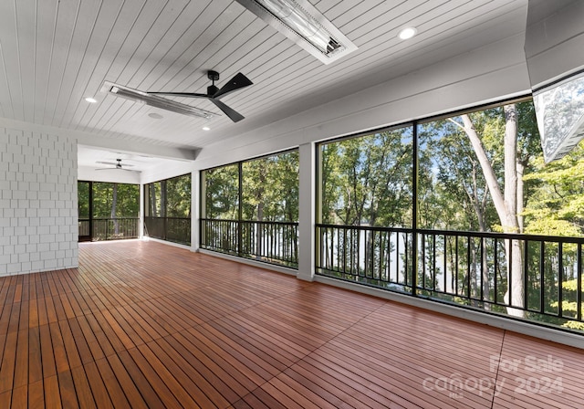 unfurnished sunroom with wooden ceiling, a healthy amount of sunlight, and ceiling fan