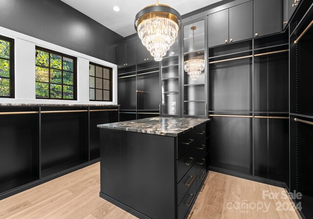 walk in closet with a chandelier and light wood-type flooring