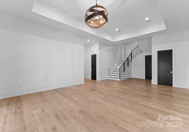 unfurnished living room featuring light hardwood / wood-style floors and a raised ceiling