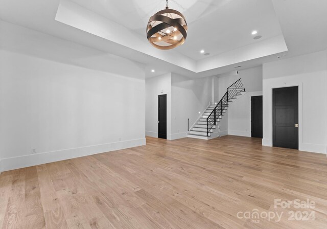 13702 Sage Thrasher Ln, Charlotte, NC 28278 - unfurnished living room featuring stairs, a raised ceiling, a chandelier, recessed lighting, and light wood-type flooring