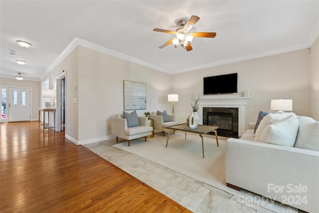 living room featuring ceiling fan, wood-type flooring, ornamental molding, and a high end fireplace