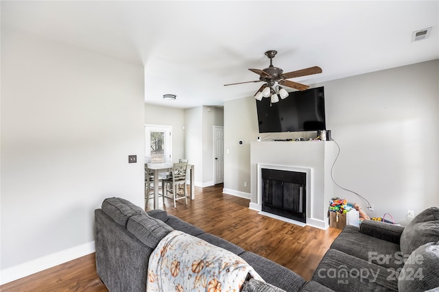 living room featuring ceiling fan and dark wood-type flooring