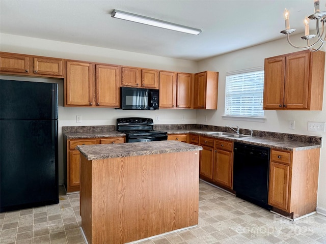 kitchen featuring dark countertops, light floors, a center island, black appliances, and a sink