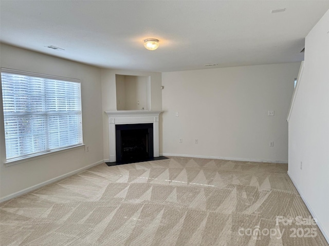 unfurnished living room with baseboards, a fireplace with flush hearth, visible vents, and light colored carpet