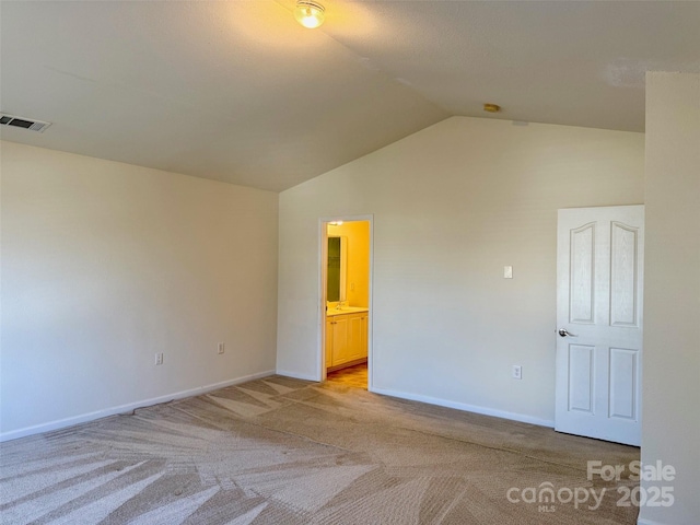 spare room with light carpet, baseboards, visible vents, and vaulted ceiling